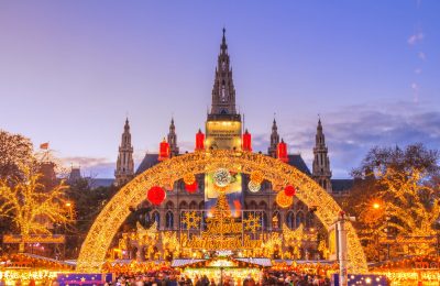 Christmas market with beautiful lights as the sun sets behind Vienna City Hall (Wiener Rathaus).